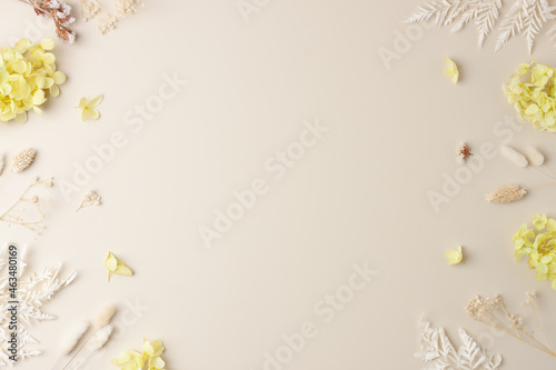 Cosmetic background with flowers on pastel beige. Flat lay  copy space