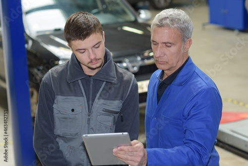 auto mechanic teacher and trainee performing tests at mechanic school © auremar