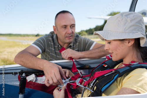 man helping woman with skydiving gear