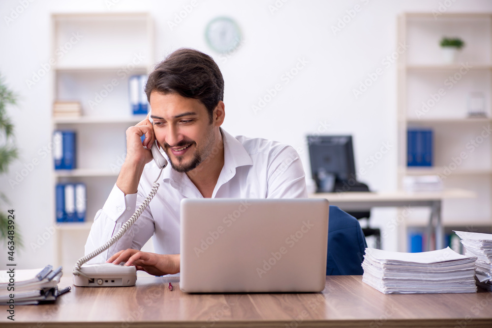 Young male employee and too much work in the office Young male employee and too much work in the office