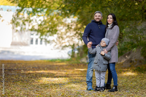 A young couple with a young son stand holding hands in an autumn park. High quality photo. Copyspace