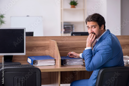 Young male employee sitting at workplace