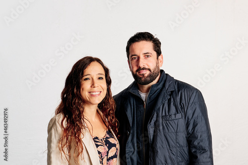 An adult couple in plaid shirts showing thumbs up to the camera and smiling against a white background