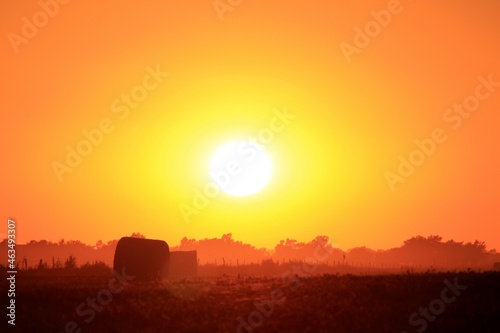 Hay Bales silhouettes at Sunset with a colorful sky south of Lyons Kansas USA out in the country. With the Sun.
