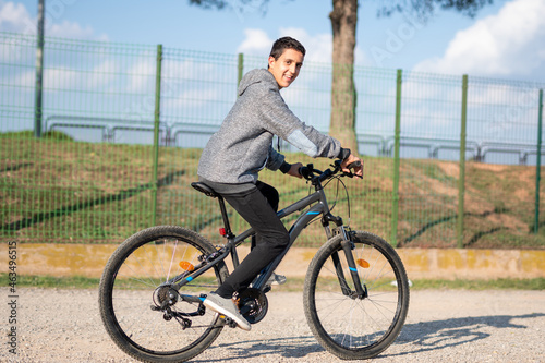 Fototapeta Naklejka Na Ścianę i Meble -  latin teenage boy with dark hair riding a bike
