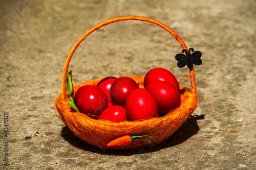 Closeup shot of red Easter eggs put in a basket and on the ground; concept holiday photo