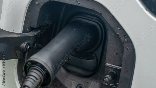 Close-up view of power supply plugged into an electric car being charged. White electric car charging. © kalyanby