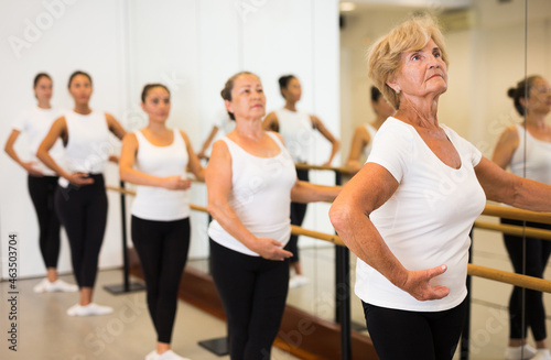 Elderly woman doing ballet steps at ballet barre in the dance studio