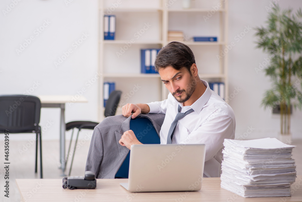 Young male employee and too much work in the office Young male employee and too much work in the office