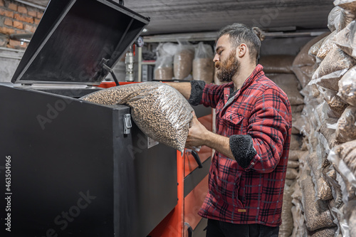 The man loads the pellets in the solid fuel boiler, working with biofuels. photo