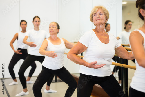 Various aged women dancing ballet during their group training.
