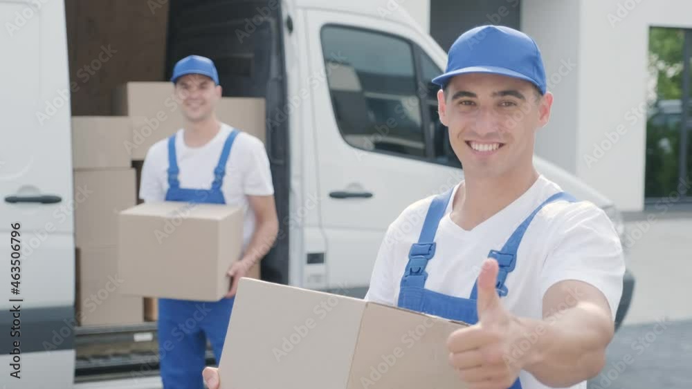 Two young workers of removal company deliver boxes to a customer's home Two young workers of removal company deliver boxes to a customer's home