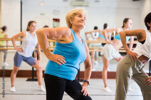 Senior woman dancing modern dance in studio with other women.