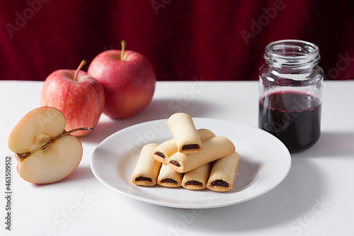 Apple cookies on a white table. Apple filled biscuits and a jar of blueberry jam.