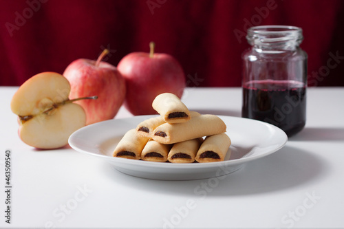 Apple cookies on a white table. Apple filled biscuits and a jar of blueberry jam.
