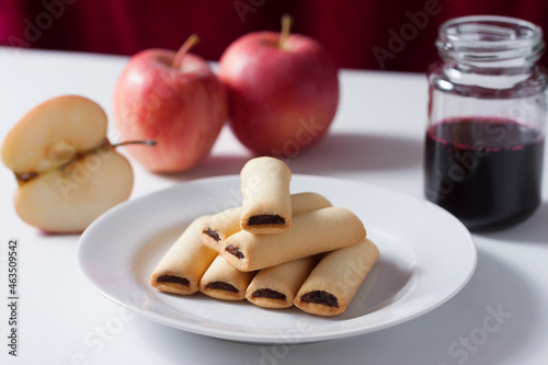 Apple cookies on a white table. Apple filled biscuits and a jar of blueberry jam.