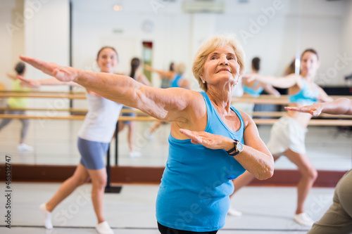 Old lady dancing with other women during group training in studio.
