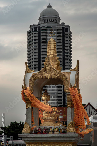 Golden statue of Phra Phrom or four-faced Buddha With a high-rise modern buildings background. Four-faced Buddha regarded in Thai culture as deity of good fortune and protection. Selective focus. photo