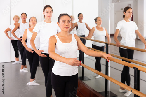 Latino woman in leotard training in ballet class with other dancers