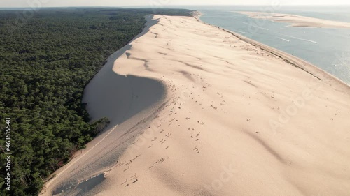 People over dune of Pilat at sunset, Arcachon basin in France. Aerial forward