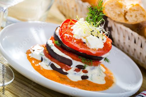 Image of tasty stack of fried eggplants and tomatoes on spicy sauce served at plate
