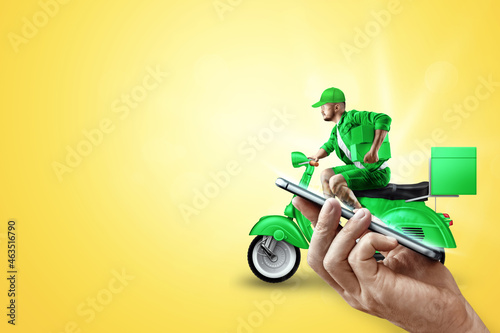 Smartphone in hand and fast delivery man on a green scooter. Delivery concept, online order, food delivery, last mile, banner, template.