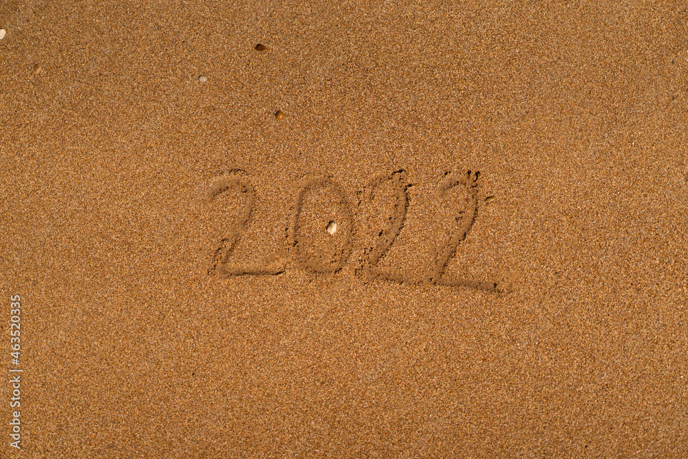 Fototapeta premium Happy New Year 2022 on the beach. Sand on a beach with a wave by the sea. Winter Vacation on the sea. New Year concept. Top view