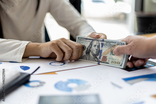 Foto Picture of two people handing over a dollar, they are business partners who are doing corrupt behavior by bribing them for illegal mutual benefit
