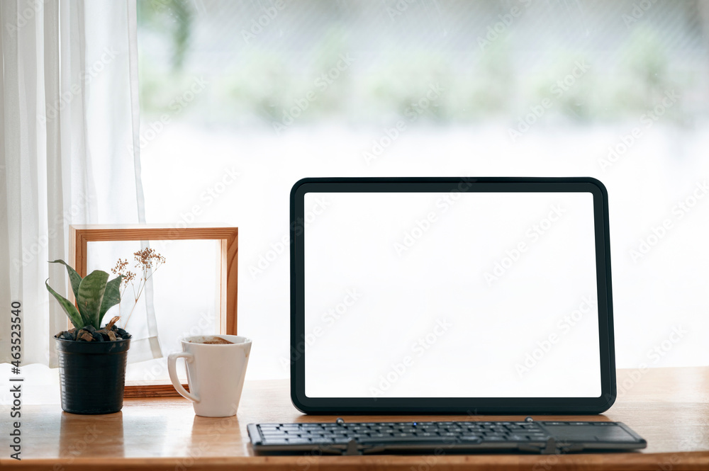 Fototapeta premium Mockup blank white screen tablet with keyboard on wooden table.