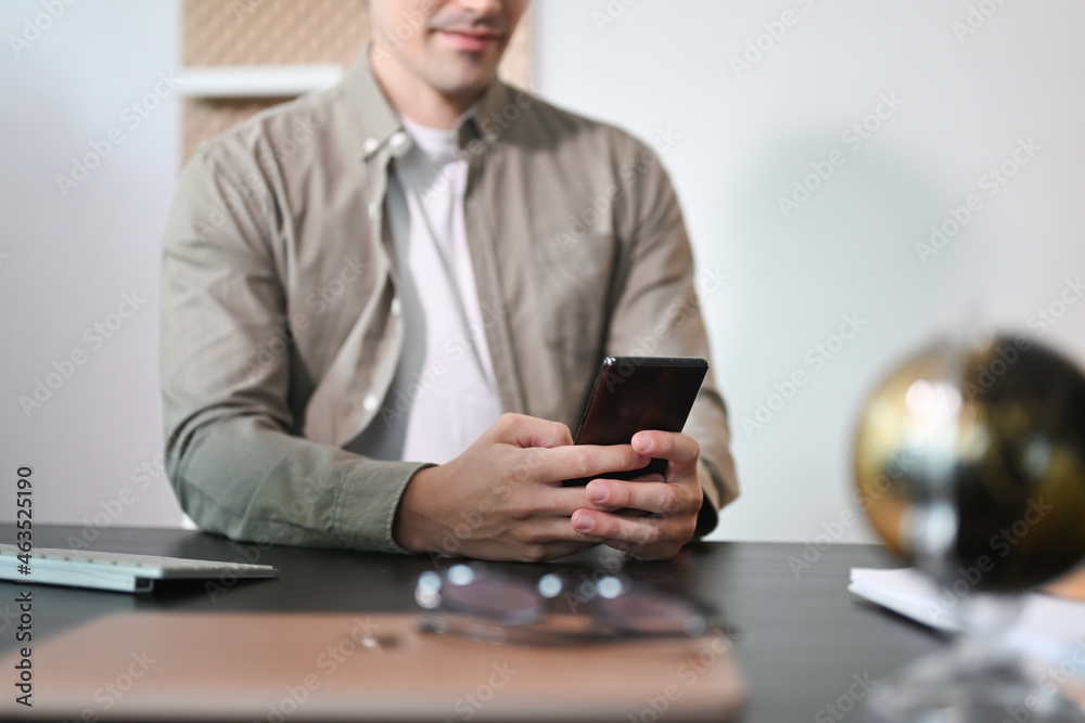 Handsome businessman sitting in his workplace and using smart phone. Handsome businessman sitting in his workplace and using smart phone.