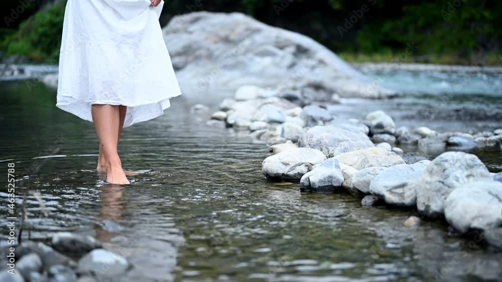 川の水に足を踏み入れる白いワンピースの女性 川の水に足を踏み入れる白いワンピースの女性