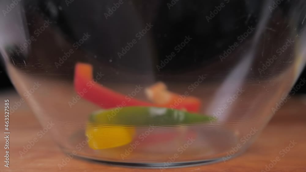 sliced fresh red, green, yellow bell pepper falling into glass bowl slow motion sliced fresh red, green, yellow bell pepper falling into glass bowl slow motion