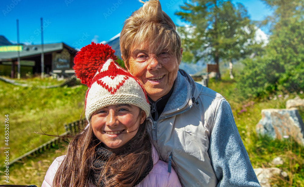 Fototapeta premium Happy young girl with her grandmother in a beautiful mountain scenario.