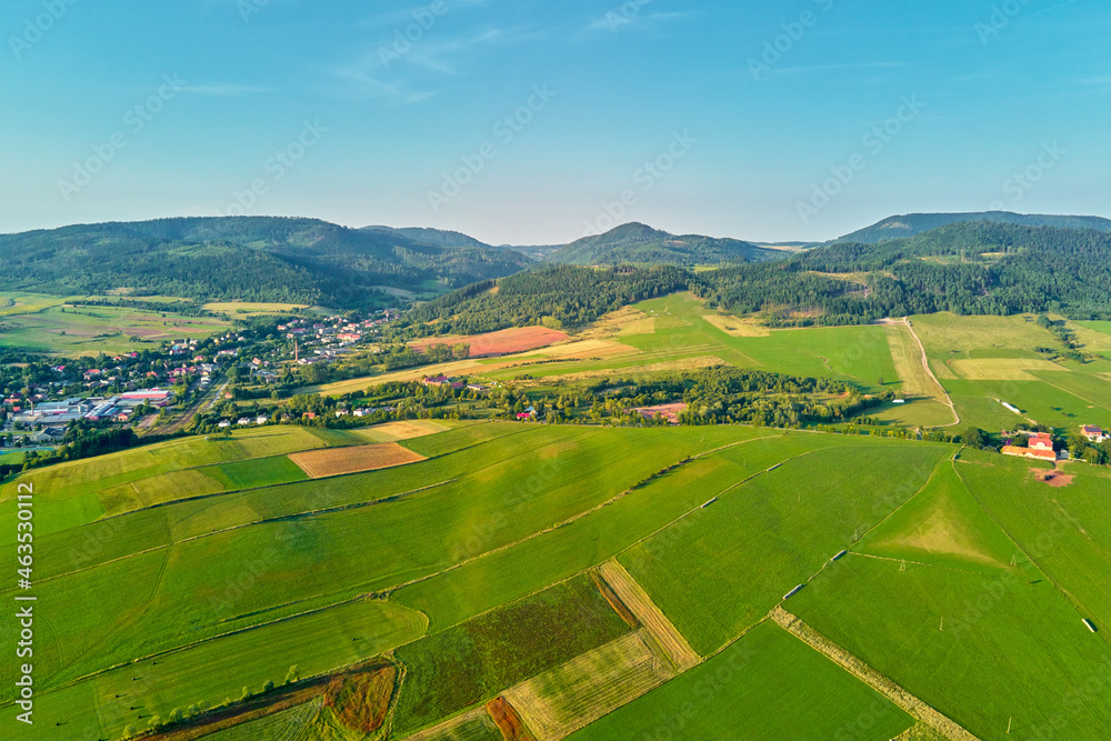 Village near mountain and agricultural fields at sunset. Nature landscapem aerial view