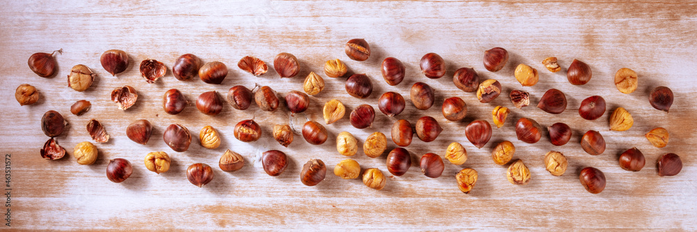 Obraz premium Chestnut panorama. Overhead flat lay panoramic banner with many chestnuts, scattered on a rustic wooden background