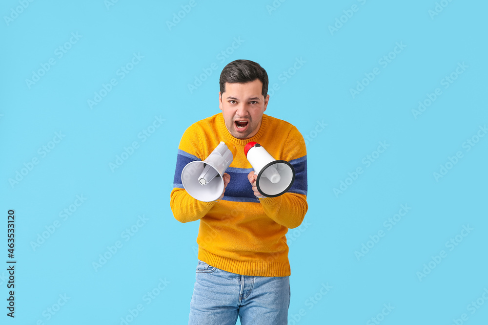 Protesting young man with megaphones on color background Protesting young man with megaphones on color background