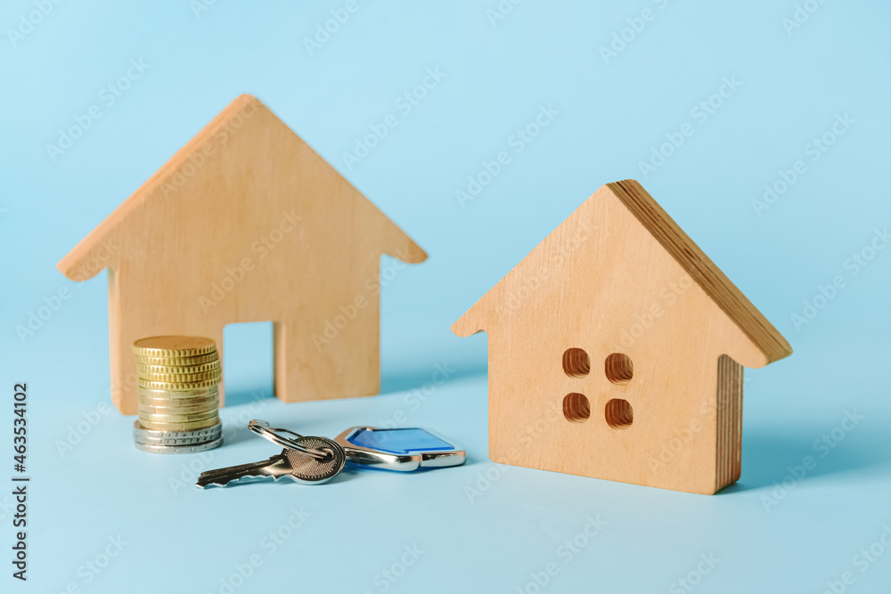 Wooden houses with key and coins on blue background Wooden houses with key and coins on blue background