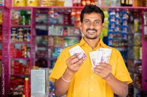Photos Happy smiling Groceries or Kirana Merchant small business owner Counting money by looking at camera - concept of Successful business, profit making, banking and finance