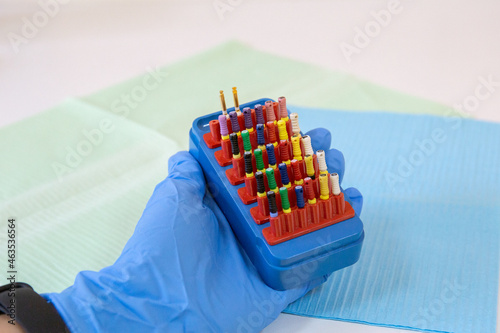 The assistant holds colorful dental endodontic tools, profiles in his hand. Tooth care and treatment concept. photo