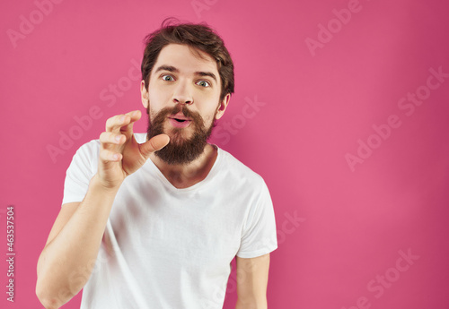 emotional man in a white t-shirt expressive look pink background
