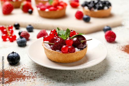 Plate with tasty berry tart on grunge background
