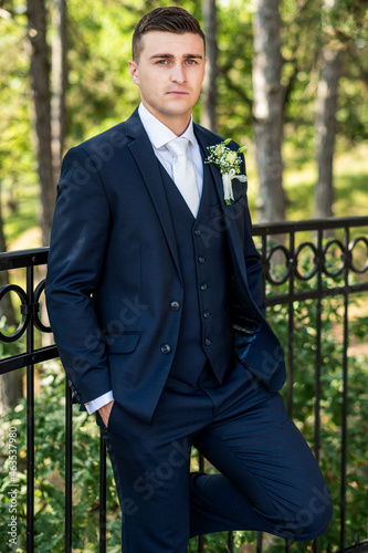 Canvastavla Handsome young groom wearing elegant dark blue suit looking at camera outdoors  portrait