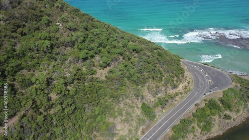 Hikers walk trail high above coastal beach road in Victoria, Australia photo