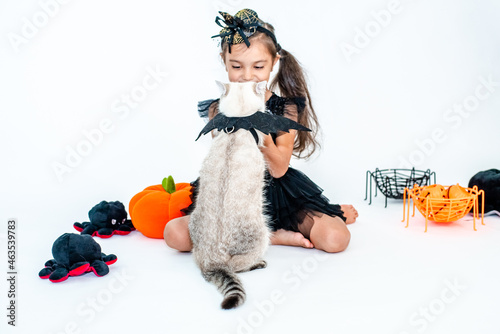 Cute european kid girl in halloween costumes with cat  having fun in halloween celebration. Photo on white background