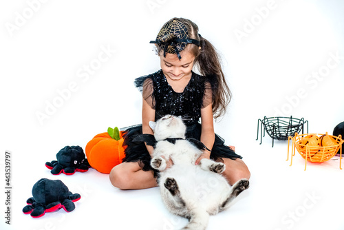 Cute european kid girl in halloween costumes with cat  having fun in halloween celebration. Photo on white background