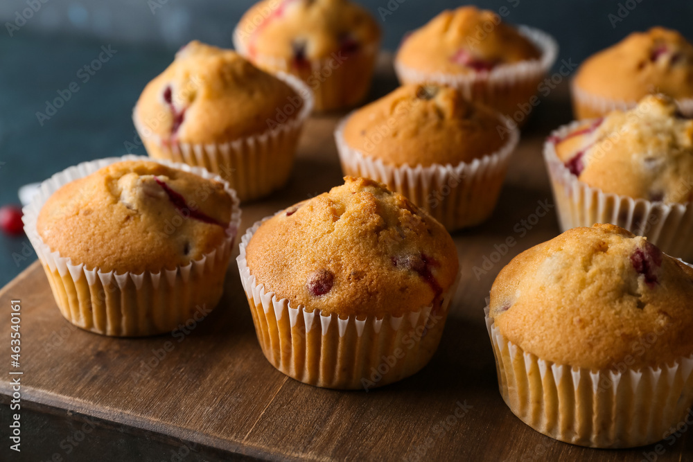 Wooden board with delicious cranberry muffins on table, closeup - obrazy, fototapety, plakaty 