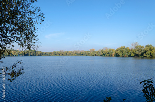 Lake in the forest surrounded by trees. Forest reservoir. Golden autumn near the water. Yellow leaves on the trees.