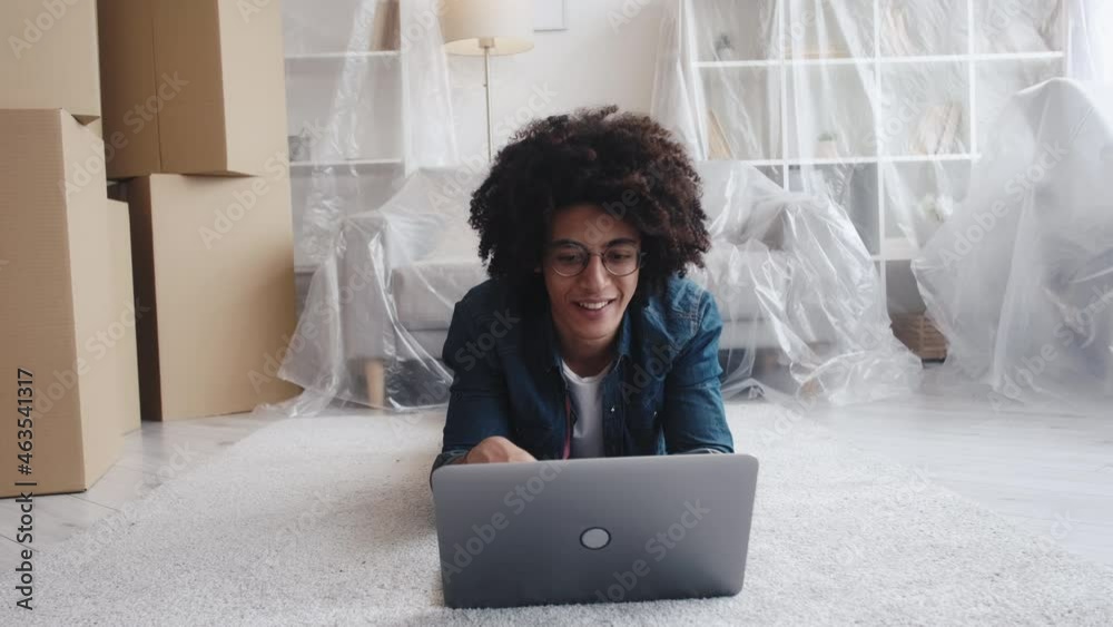 Flat online. Property website. Real estate. Inspired pensive Arab guy searching for new place to move browsing Internet using laptop at home interior with boxes isolated furniture.