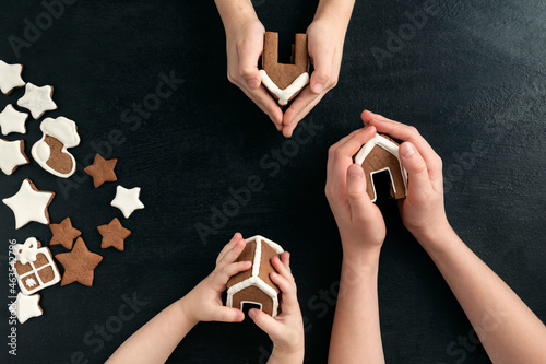 Three children are holding gingerbread houses. Top view on black background