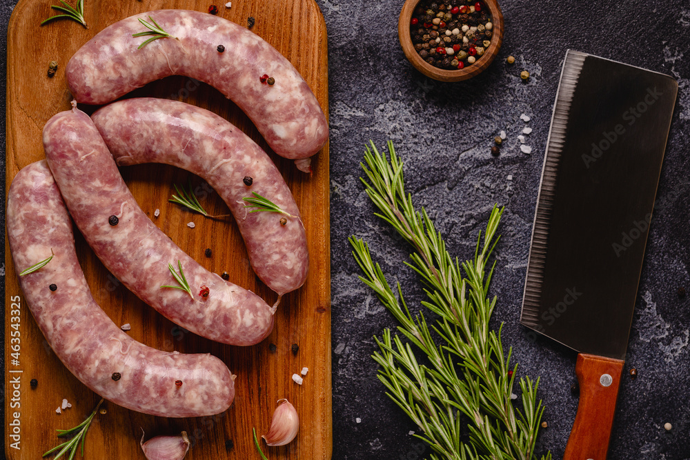 Raw sausages and ingredients for cooking on a black stone table. Raw sausages and ingredients for cooking on a black stone table.
